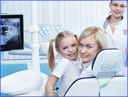 Young woman and daughter in an exam chair, receiving dental treaments.